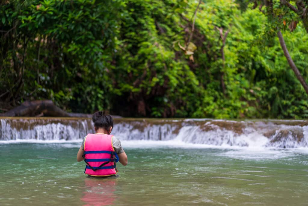 Niño con chaleco salvavidas en una piscina natural.