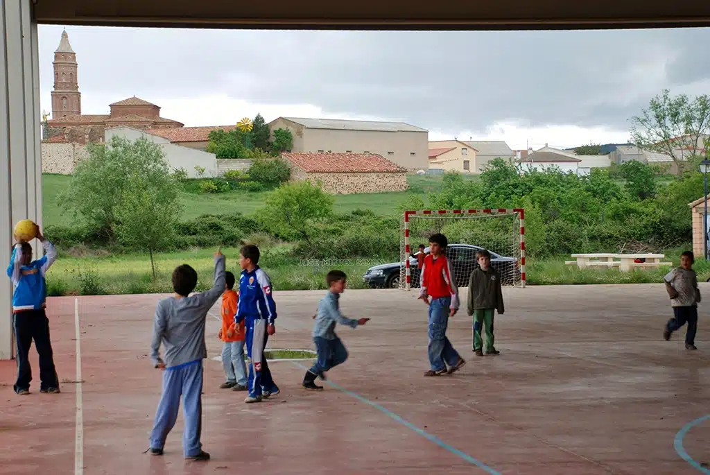 El medallista olímpico Jesús Vallejo (de rojo), jugando al fútbol en el pabellón de Loscos, en una imagen de su infancia. Al fondo, puede apreciarse el pueblo.