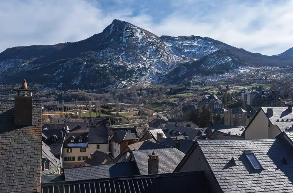 Conjunto de tejados de Sallent de Gállego, donde se pueden ver ‘espantabrujas’ en casas modernas. Al fondo, el pico Pacino. Por NéstorMN.