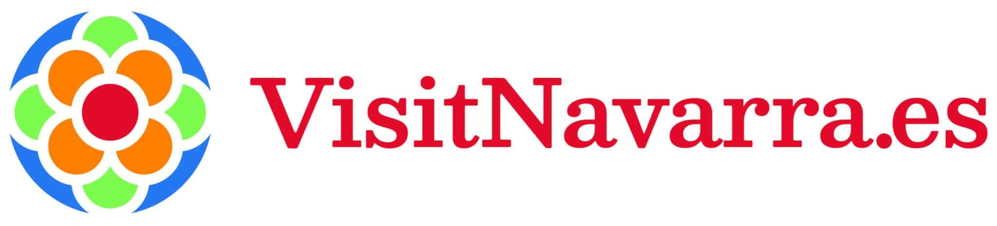Logotipo con un colorido diseño en forma de flor a la izquierda, con pétalos rojos, naranjas, verdes y azules, y el texto VisitNavarra.es en negrita y fuente roja a la derecha.