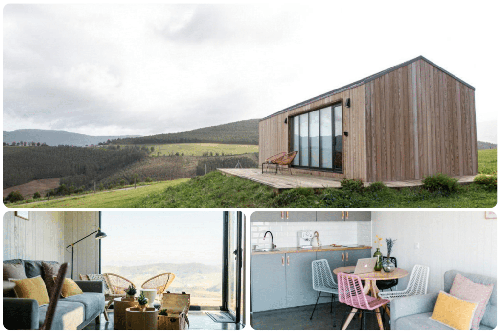 Una casita moderna con revestimiento de madera se asienta en una ladera cubierta de hierba con vistas a onduladas colinas verdes; dentro, hay una acogedora sala de estar y una cocina compacta con una mesa de comedor y sillas de colores.
