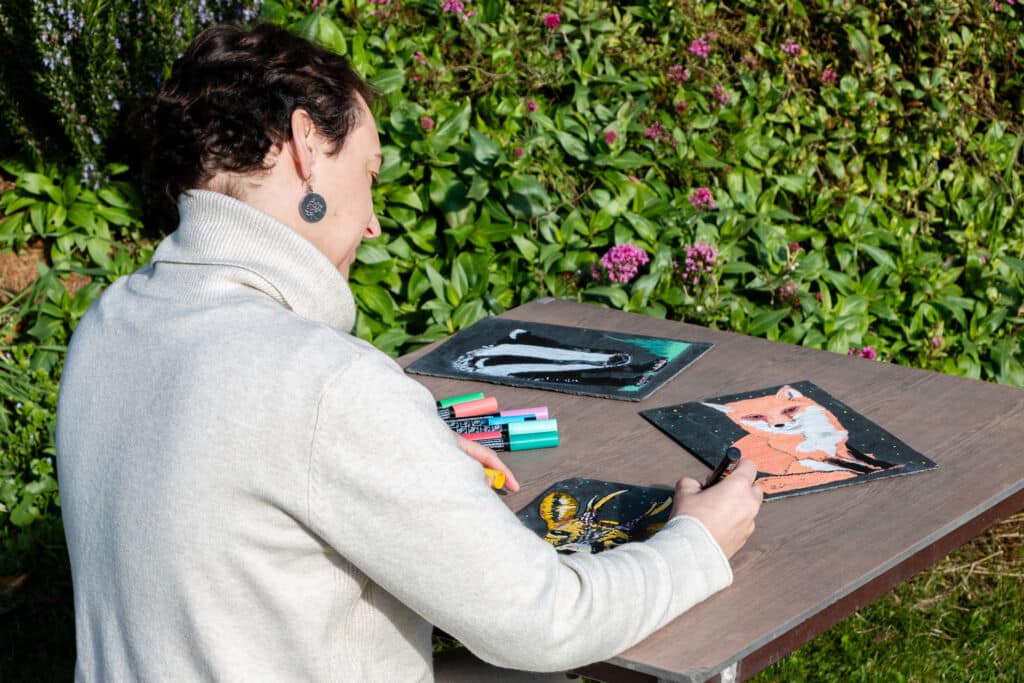 Una mujer sentada en una mesa con material de arte.