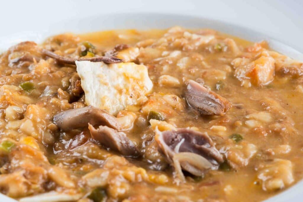 Un primer plano de un sustancioso guiso con trozos de carne, verduras y una salsa cremosa, servido en un cuenco blanco.
