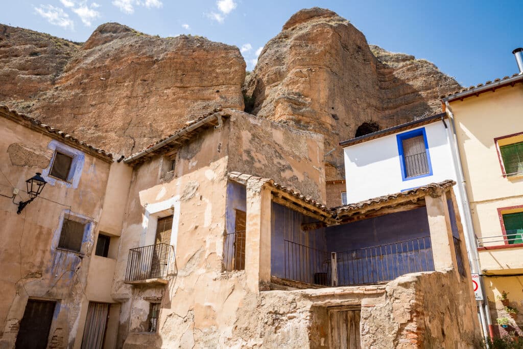 Antiguas casas de piedra enclavadas al pie de un imponente acantilado rocoso.