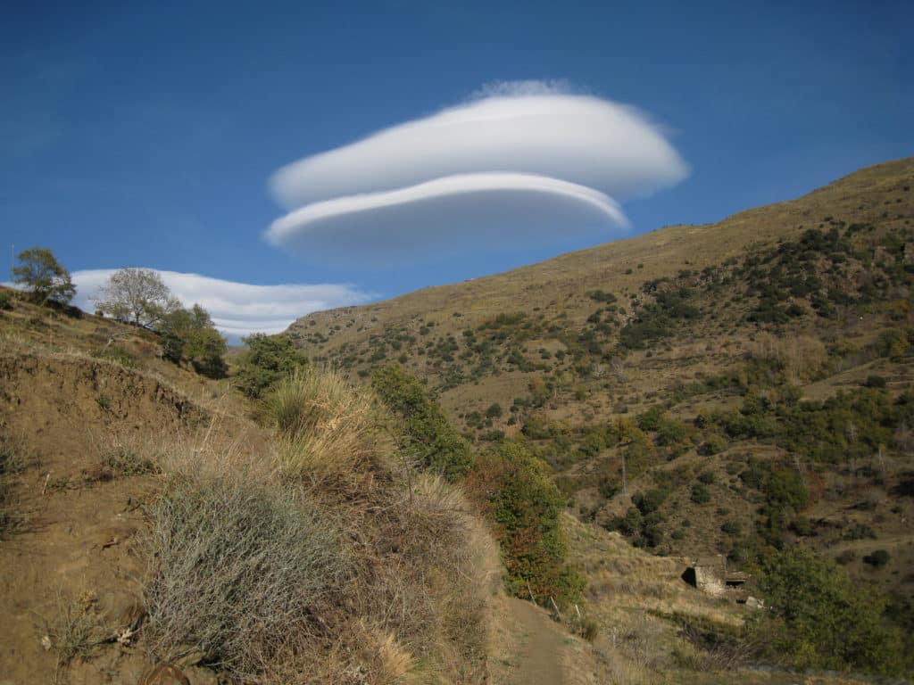 Lenticular cloud hangs over village in Sierra Nevada mountains, Spain