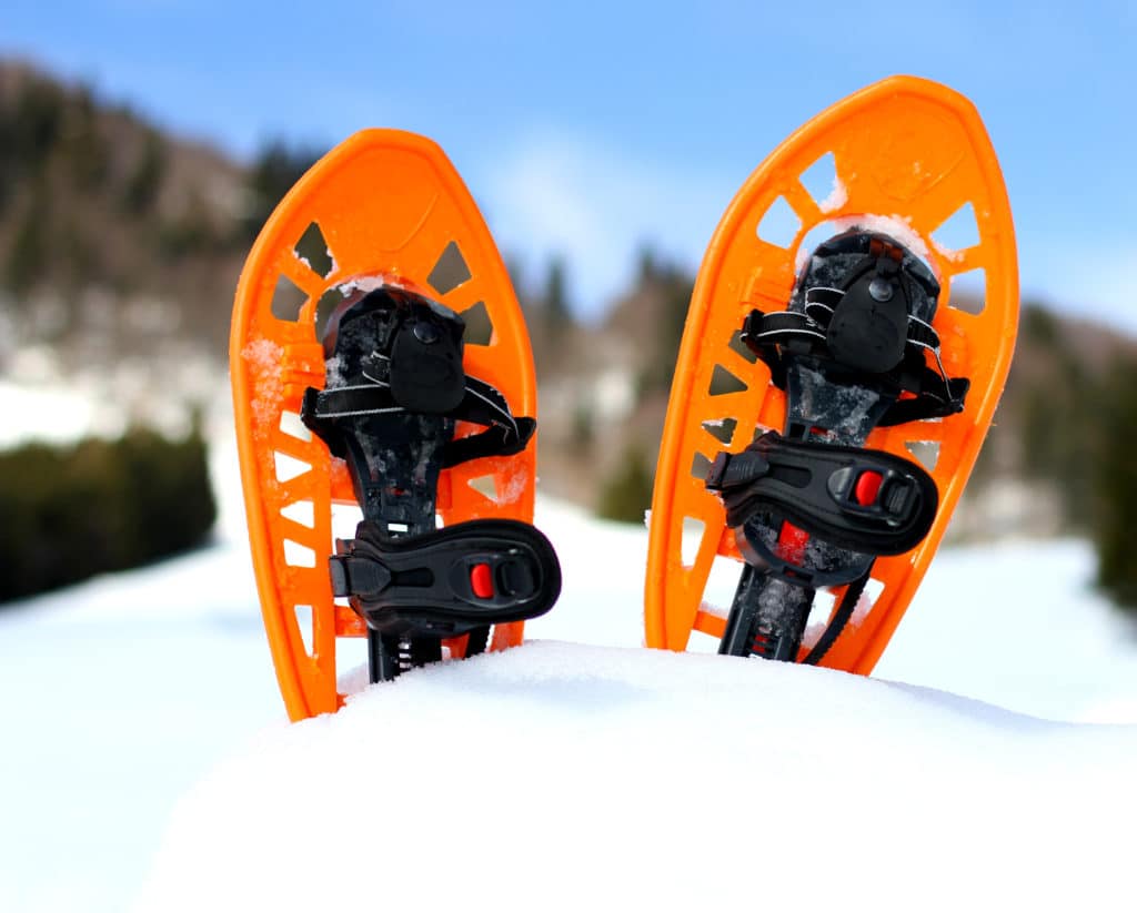 Orange snowshoes for walking on the white snow and blue sky