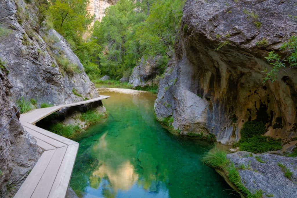 The Matarranya river runs between large rocks where the trees hang, forming a spectacular landscape with its transparent green waters. The Parrizal. Beseit, Matarranya, Aragon, Spain